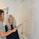 Två personer som står framför en whiteboardtavla.