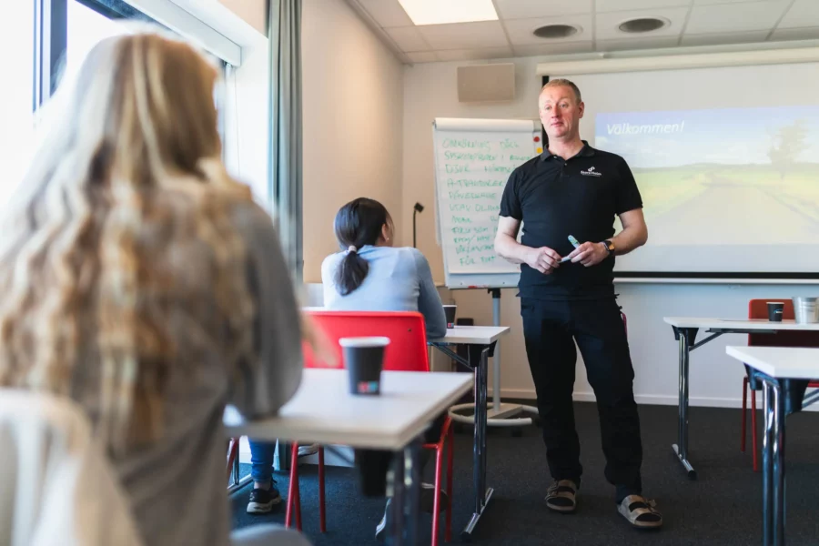 Bild på en manlig lärare som står och föreläser i ett klassrum