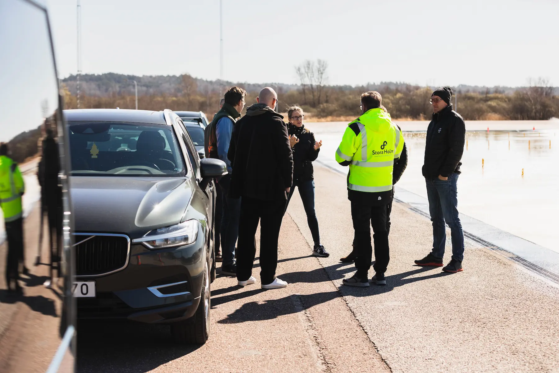 En grupp personer står på halkbanan och samtalar med en instruktör