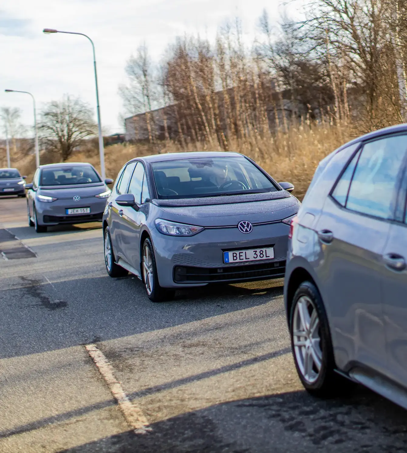 Gråa bilar som står på rad på en asfaltsväg