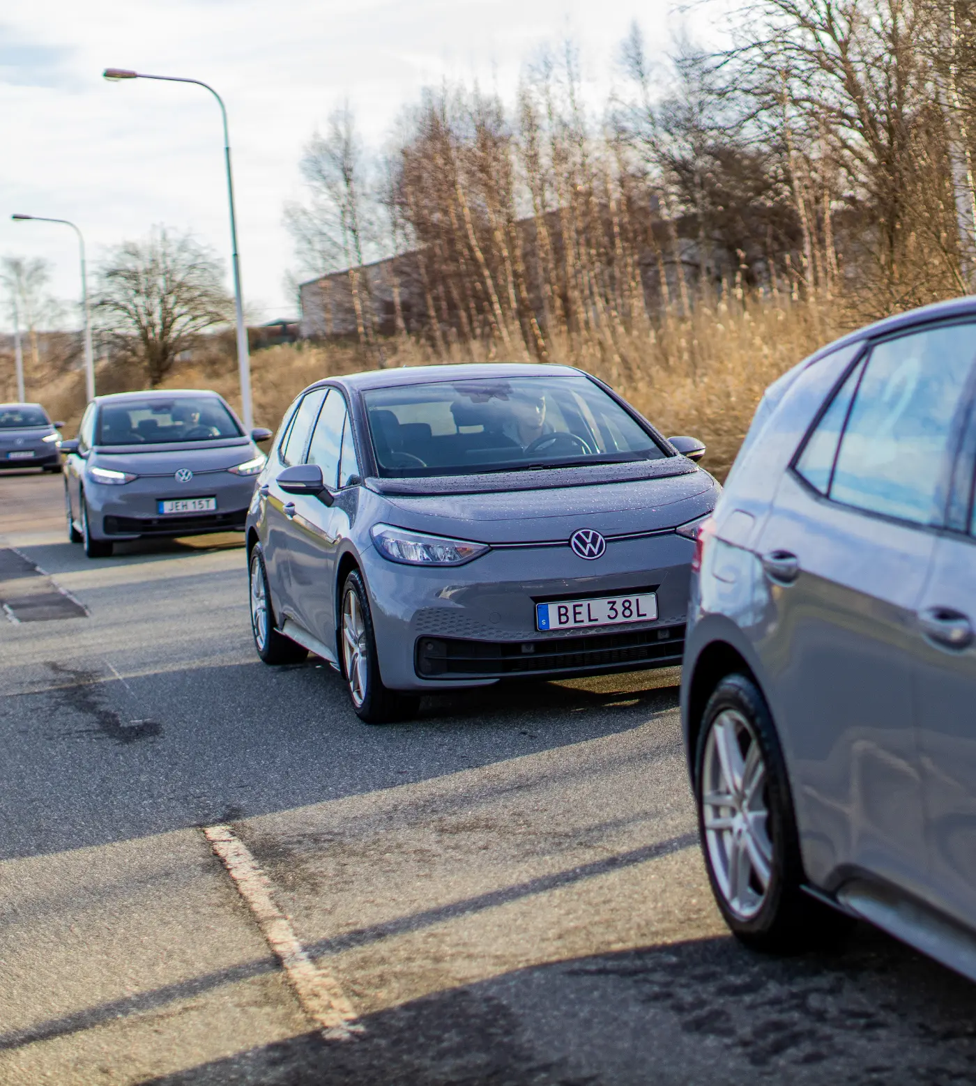 fyra gråa bilar som står på en rad på en asfaltsväg