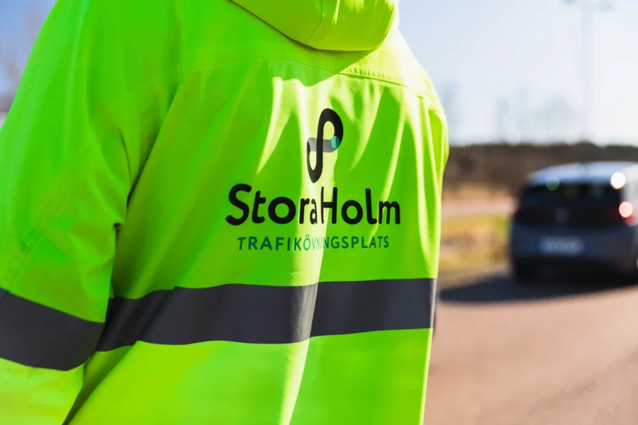 Baksidan av en varseljacka där det står stora holm trafikövningsplats står